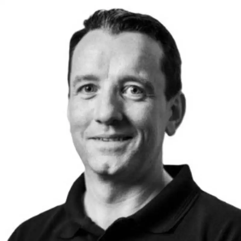 Black and white portrait of a man with short hair and a slight smile, wearing a dark polo shirt.